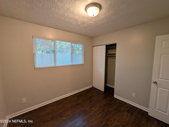 unfurnished bedroom featuring a textured ceiling, a closet, and dark hardwood / wood-style floors