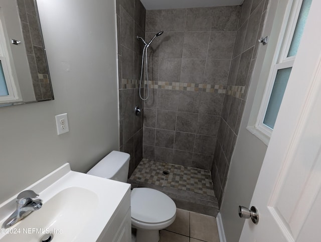 bathroom featuring tile patterned floors, vanity, toilet, and a tile shower