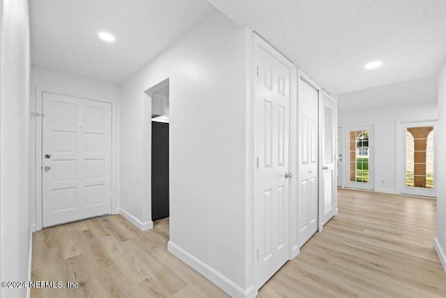 hall with light hardwood / wood-style floors and a textured ceiling