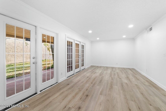 empty room featuring light wood-type flooring and ornamental molding