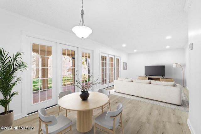 dining space with french doors, light wood-type flooring, plenty of natural light, and crown molding