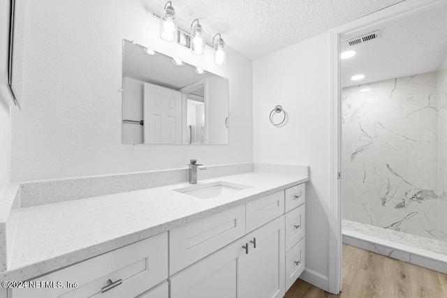 bathroom with a shower, vanity, wood-type flooring, and a textured ceiling