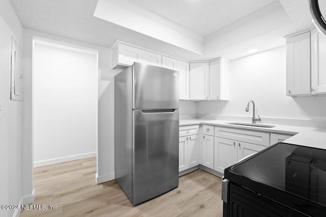 kitchen with white cabinets, electric range oven, crown molding, and stainless steel refrigerator