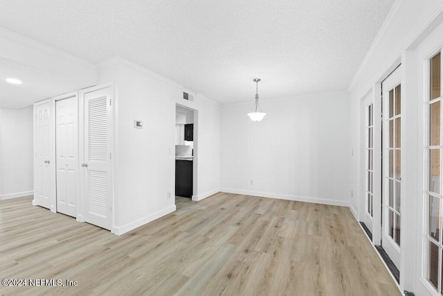 interior space with light wood-type flooring, a textured ceiling, and crown molding