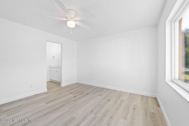 empty room with a textured ceiling, light wood-type flooring, and ceiling fan