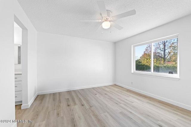 empty room with ceiling fan, a textured ceiling, and light hardwood / wood-style flooring