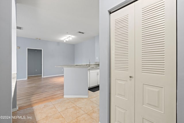 kitchen with white cabinets, light wood-type flooring, kitchen peninsula, and sink