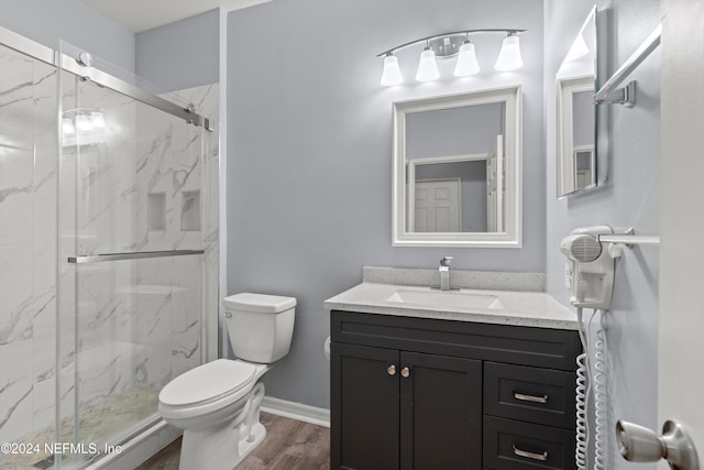 bathroom with hardwood / wood-style floors, vanity, toilet, and a shower with door