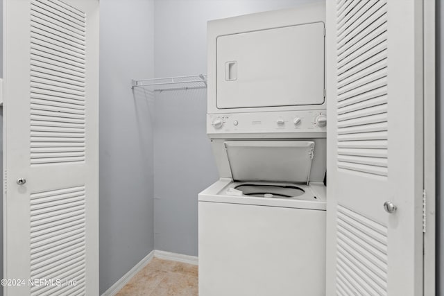 clothes washing area featuring light tile patterned flooring and stacked washer and clothes dryer