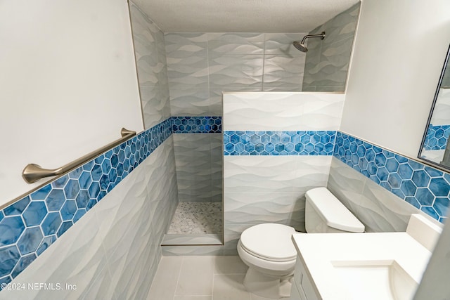 bathroom with a tile shower, tile patterned flooring, and tile walls