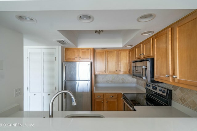 kitchen featuring a raised ceiling, decorative backsplash, crown molding, and appliances with stainless steel finishes