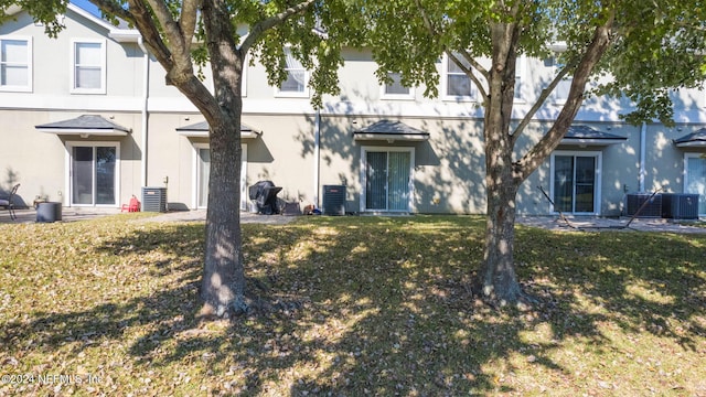 rear view of house with cooling unit and a yard