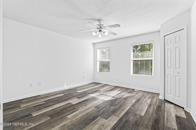 unfurnished room featuring a textured ceiling, ceiling fan, and dark wood-type flooring