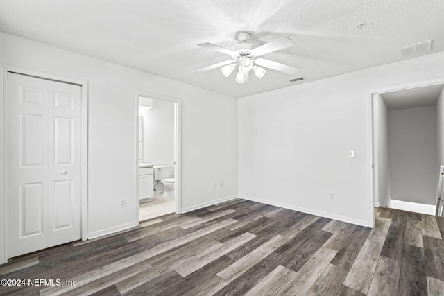 unfurnished bedroom featuring dark hardwood / wood-style floors, ceiling fan, ensuite bathroom, and a closet