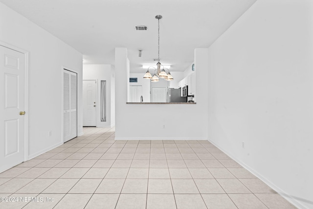 unfurnished living room with light tile patterned floors and an inviting chandelier