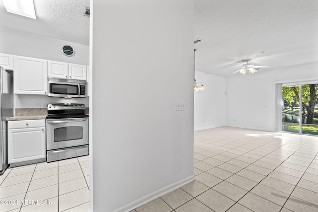 kitchen featuring a textured ceiling, white cabinets, light tile patterned floors, and appliances with stainless steel finishes