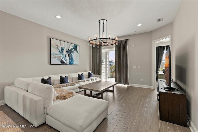 living room featuring hardwood / wood-style flooring, a textured ceiling, and an inviting chandelier