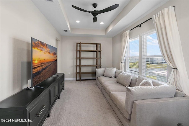 carpeted living room featuring ceiling fan and a tray ceiling