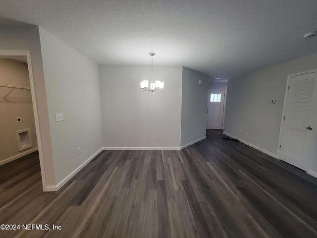 unfurnished dining area with dark hardwood / wood-style flooring, a textured ceiling, and an inviting chandelier