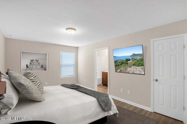 bedroom with ensuite bathroom, wood-type flooring, and a textured ceiling