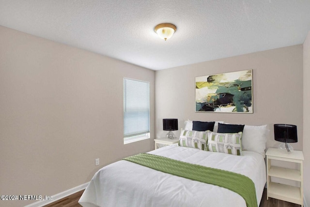 bedroom with dark hardwood / wood-style floors and a textured ceiling