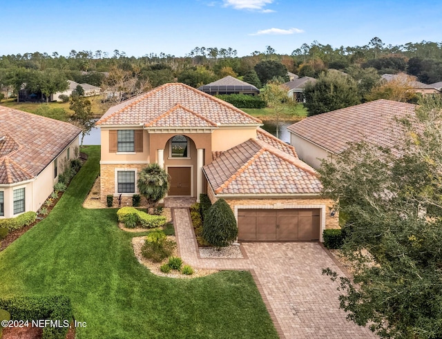 mediterranean / spanish home featuring a front yard and a garage