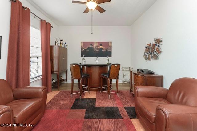 interior space with bar area, ceiling fan, and wood-type flooring