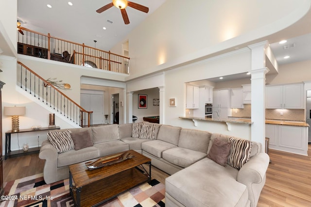 living room featuring a high ceiling, light hardwood / wood-style flooring, and ceiling fan