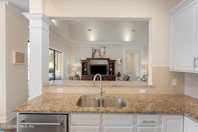 kitchen featuring white cabinets, sink, stainless steel dishwasher, light stone countertops, and decorative columns