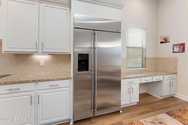 kitchen with white cabinets, decorative backsplash, stainless steel built in fridge, and light wood-type flooring