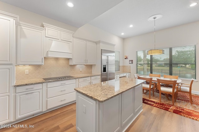 kitchen with built in fridge, black electric stovetop, white cabinetry, and light wood-type flooring