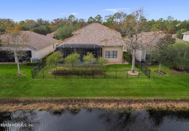 back of property featuring a lawn, glass enclosure, and a water view