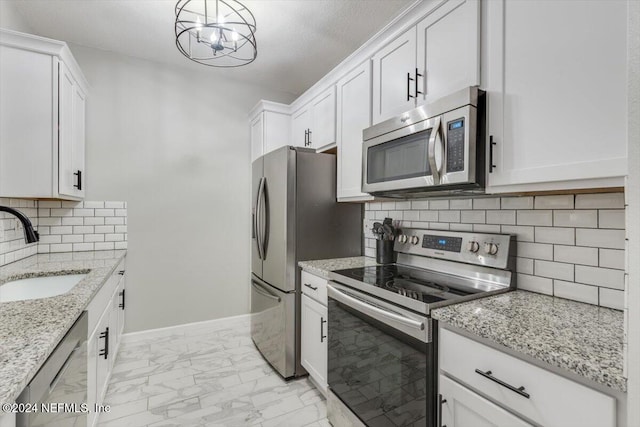 kitchen with sink, stainless steel appliances, an inviting chandelier, tasteful backsplash, and white cabinets