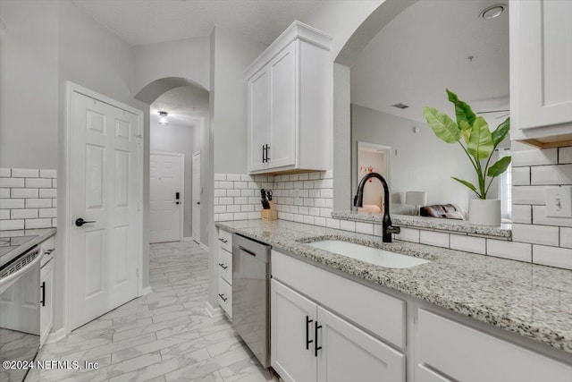 kitchen with backsplash, white cabinetry, dishwasher, and sink