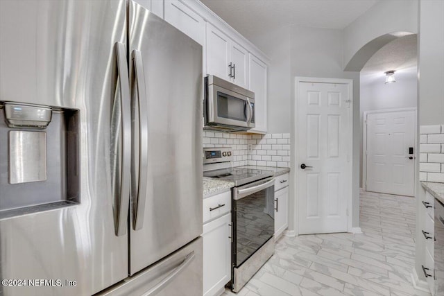 kitchen with light stone counters, backsplash, a textured ceiling, white cabinets, and appliances with stainless steel finishes