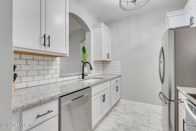 kitchen with decorative backsplash, light stone countertops, stainless steel appliances, sink, and white cabinets