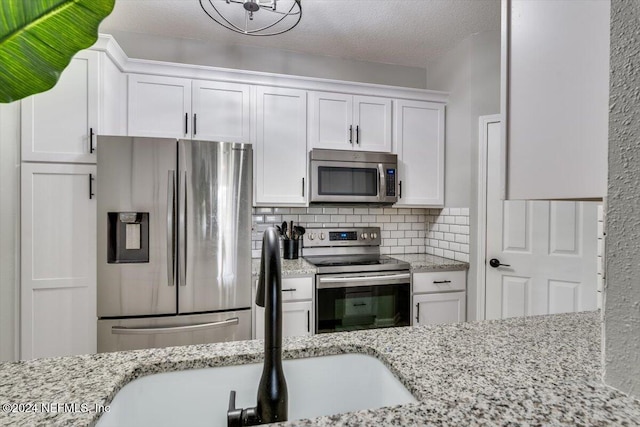 kitchen featuring decorative backsplash, light stone counters, white cabinetry, and stainless steel appliances