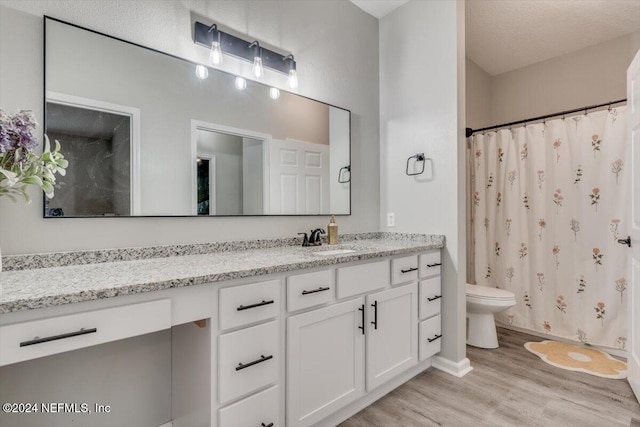 bathroom featuring hardwood / wood-style floors, vanity, toilet, and a textured ceiling