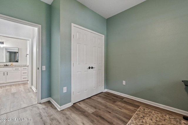 unfurnished bedroom with ensuite bathroom, sink, and wood-type flooring