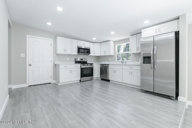 kitchen with sink, white cabinets, light hardwood / wood-style flooring, and appliances with stainless steel finishes