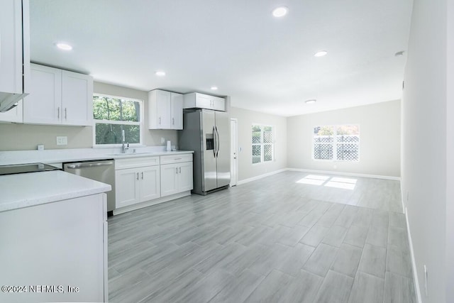 kitchen with plenty of natural light, white cabinets, light hardwood / wood-style floors, and appliances with stainless steel finishes