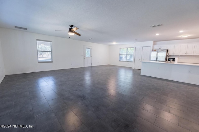 unfurnished living room featuring ceiling fan and a wealth of natural light