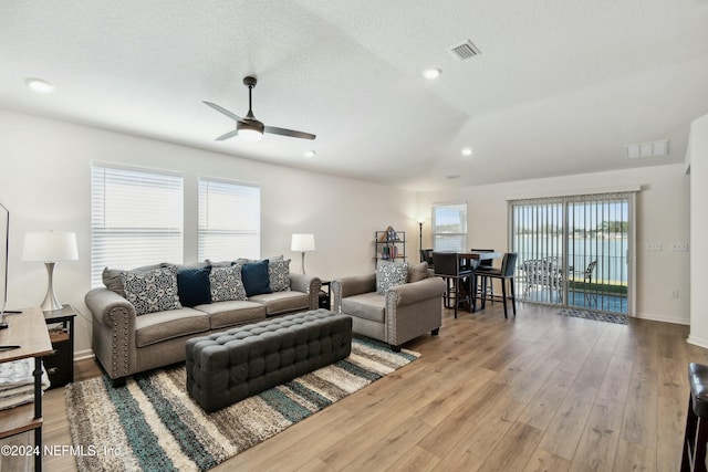 living room featuring ceiling fan, light hardwood / wood-style floors, and a textured ceiling