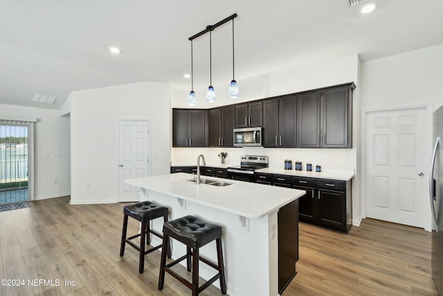 kitchen featuring a center island with sink, decorative light fixtures, light hardwood / wood-style floors, and appliances with stainless steel finishes