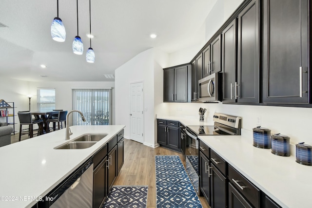 kitchen with decorative light fixtures, light hardwood / wood-style floors, sink, and stainless steel appliances