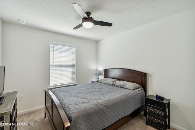 carpeted bedroom featuring ceiling fan and a textured ceiling