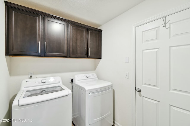 clothes washing area featuring cabinets, separate washer and dryer, and a textured ceiling