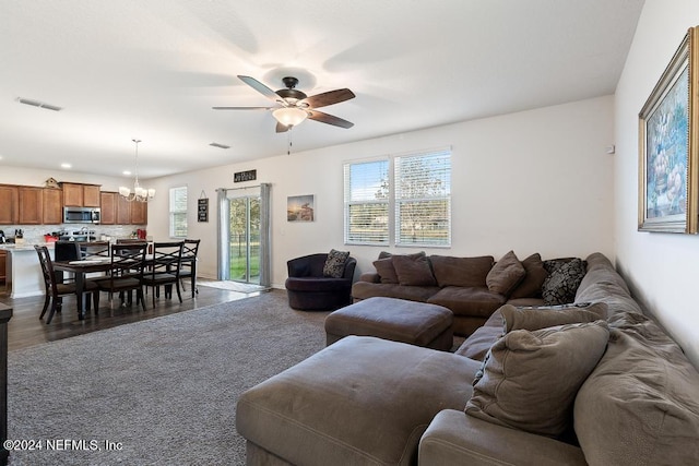 living room with ceiling fan with notable chandelier and dark hardwood / wood-style flooring