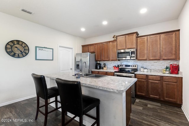 kitchen featuring dark hardwood / wood-style flooring, stainless steel appliances, a center island with sink, and a breakfast bar area