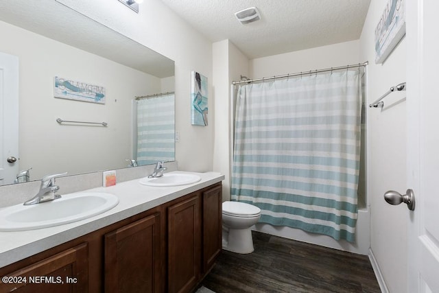 full bathroom featuring vanity, a textured ceiling, shower / bath combo with shower curtain, hardwood / wood-style floors, and toilet